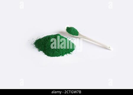 Cuillère blanche avec tas de chlorella ou d'algues spiruline, ou matcha, sur fond clair. Poudre de concept superalimentaire. Banque D'Images