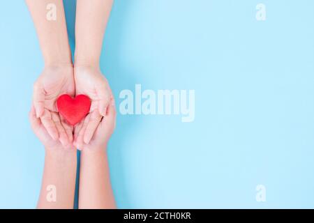 Femme et enfant tenant le cœur sur fond bleu clair. Concept pour la charité, l'assurance maladie, l'amour, journée internationale de cardiologie. Journée mondiale du cœur ou Banque D'Images