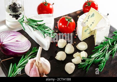 Le fromage assorti de légumes et de romarin est sur une sombre carte Banque D'Images