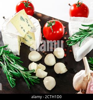 Le fromage assorti de légumes et de romarin est sur une sombre carte Banque D'Images
