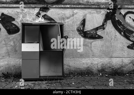 Un vieux placard cassé se trouve devant un mur pulvérisé d'argent, de gros déchets dans la rue, un placard cassé dans la rue Banque D'Images