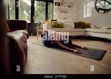 Vue latérale de la jeune femme africaine faisant de l'exercice de forme physique à chez vous sur un tapis de yoga Banque D'Images