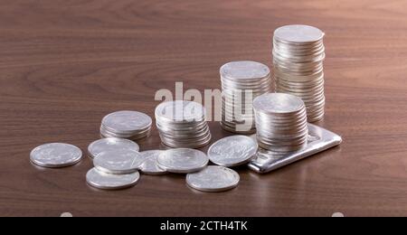 Piles de pièces de monnaie et de barres argentées sur une table en bois Banque D'Images