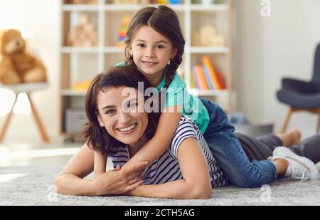 Une mère heureuse et souriante avec une adorable petite fille couchée sur un tapis dans la chambre de bébé Banque D'Images