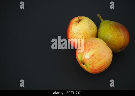 De belles poires et une pomme sur fond noir. Image horizontale. Banque D'Images