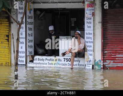 Mumbai, Inde. 23 septembre 2020. Un homme s'assoit à l'extérieur de son magasin inondé alors qu'il parle sur son téléphone.de fortes pluies ont heurté la ville, ce qui a entraîné l'engorgement des eaux et des personnes ayant de la difficulté à faire à travers les eaux inondées. Crédit : SOPA Images Limited/Alamy Live News Banque D'Images
