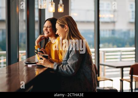 Rencontre de jeunes amis pour un café dans un café. Deux amies qui se font café et sourient. Banque D'Images