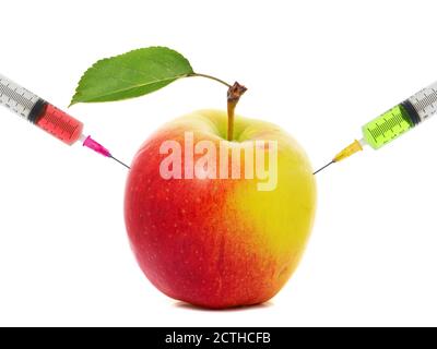 Seringues coincées dans une pomme. Concept de modification génétique des fruits et de maturation artificielle Banque D'Images