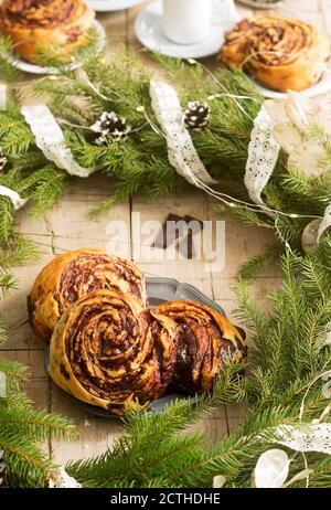 Muffins au chocolat escargot servi avec du café sur l'arrière-plan d'une couronne de branches de sapin et les cônes. Style rustique. Banque D'Images