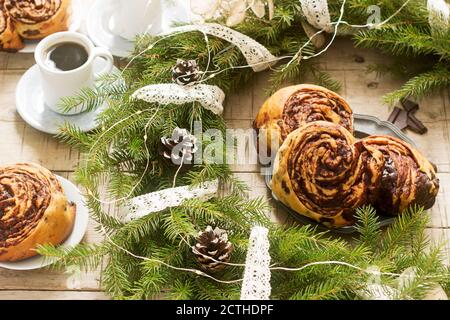 Muffins au chocolat escargot servi avec du café sur l'arrière-plan d'une couronne de branches de sapin et les cônes. Style rustique. Banque D'Images