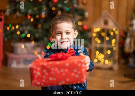 Noël fabuleux, petit garçon tenant une grande boîte rouge avec un cadeau de Santa. Banque D'Images