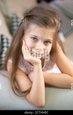 Portrait d'une petite fille qui se trouve sur le canapé, s'appuyant sur son bras. Banque D'Images