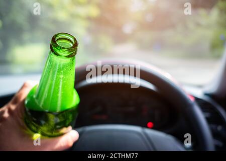 L'homme qui tient et boit de la bière tout en conduisant la voiture Banque D'Images