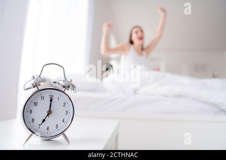 Photo de charmante jeune femme lit blanc draps couverture vêtements radio-réveil en métal qui sonne à 7 heures tôt le matin et qui baille paresseux bâillements de travailleurs Banque D'Images