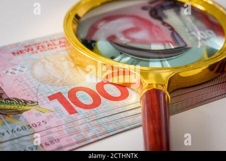 Un lot de billets de cent dollars néo-zélandais avec une loupe sur le dessus. Le concept de banque et d'investissement Banque D'Images