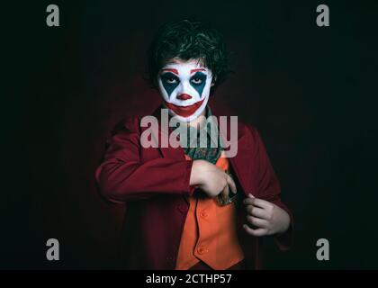 enfant habillé comme clown sur fond sombre Banque D'Images