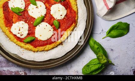 Pizza maison en croûte de chou-fleur recouverte de feuilles de basilic frais Banque D'Images