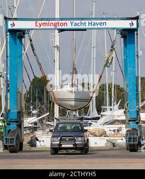 Levage D'UN bateau J 80 suspendu sur des sangles dans le Eau utilisant UNE grue spécialisée à Lymington Yacht Haven Royaume-Uni Banque D'Images