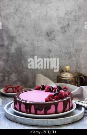 Gâteau à la mousse de curricassis décoré de petits gâteaux et de framboises. Banque D'Images