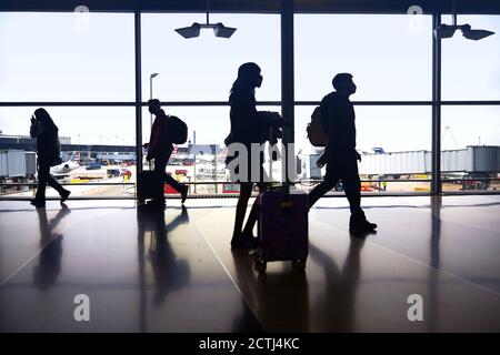 Silhouettes de voyageurs aériens se déplacent entre les terminaux pour prendre des vols pendant une pandémie à l'aéroport O'Hare de Chicago Banque D'Images