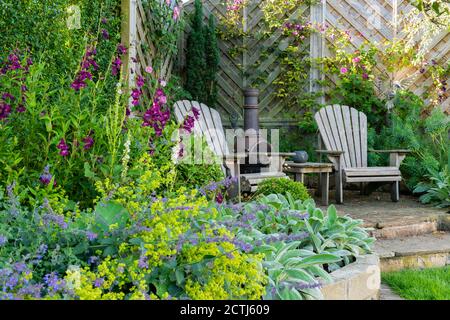 Beau jardin privé paysagé (design contemporain, plantes colorées à la frontière, terrasse, clôture, chiminea ornementale) - Yorkshire, Angleterre, Royaume-Uni Banque D'Images