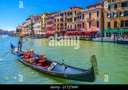 Venise, Italie, 13 septembre 2019 : gondolier et touristes en gondole bateau traditionnel naviguant sur l'eau du Grand Canal avec architecture vénitienne typique bâtiments colorés arrière-plan Banque D'Images
