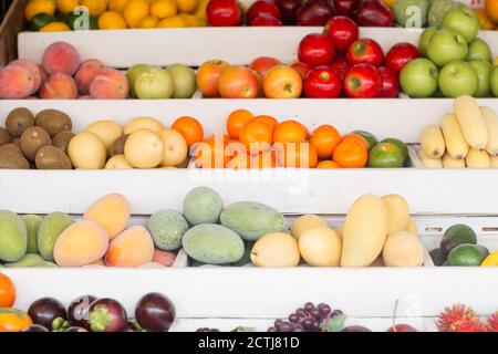 De nombreux fruits de saison frais à vendre sont exposés sur un stand sur un marché agricole local. Banque D'Images