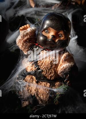 Poupée de creepy. Décoration d'Halloween. La poupée bébé est attrapée dans les toiles d'araignée et porte un masque sombre. Concept d'horreur. Banque D'Images