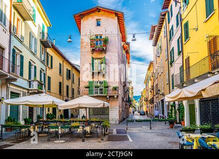Bâtiment traditionnel coloré avec balcons et fenêtres à volets dans une rue italienne typique, tables et tente de restaurant de rue, centre historique de Brescia, Lombardie, Italie du Nord Banque D'Images