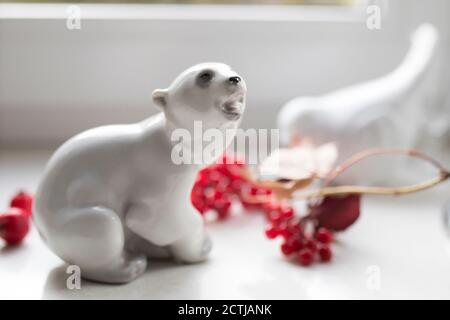 figurine en porcelaine d'un ours polaire avec une branche de viburnum sur le rebord de la fenêtre. Photo pour Instagram Banque D'Images