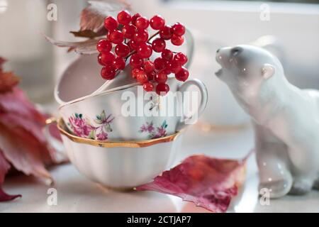 figurine en porcelaine d'un ours polaire avec une branche de viburnum dans la tasse sur le rebord de la fenêtre. Photo pour Instagram Banque D'Images