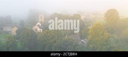 L'église Saint-Wilfrid de Burnsall devient visible lorsque le soleil levant brûle l'épais brouillard qui entoure le joli village des Yorkshire Dales. Banque D'Images