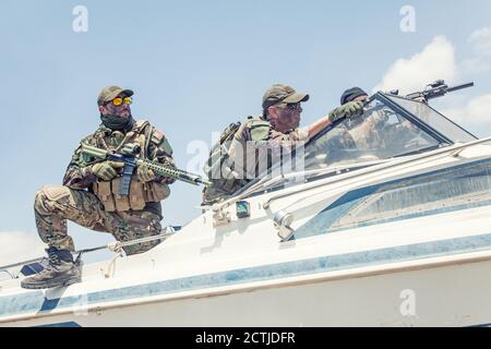 Les combattants de l'équipe anti-terroriste, les soldats de l'équipe de sceaux armés de fusil de service avec soupir optique et silencieux, se précipitant sur un hors-bord, criant des ordres aux camarades, pourchassant et attaquant l'ennemi sur l'eau Banque D'Images