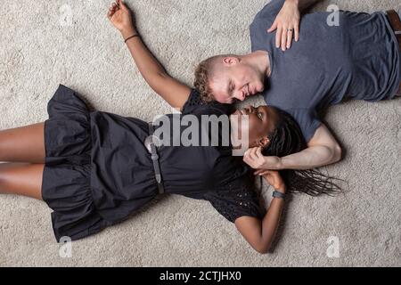 Un couple multiracial posé sur le sol en regardant chacun autre Banque D'Images