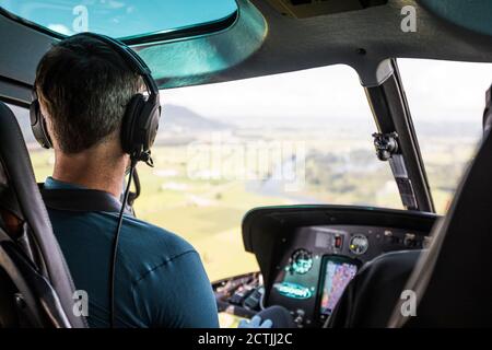 Pilote d'hélicoptère survolant les terres agricoles en contrebas. Banque D'Images