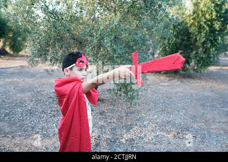 un enfant déguisé en super-héros rouge pointe son épée à les fantômes Banque D'Images