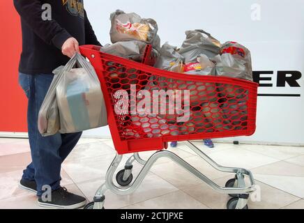 Un homme poussant un chariot complet de sacs d'épicerie en plastique, Queensland, Australie Banque D'Images