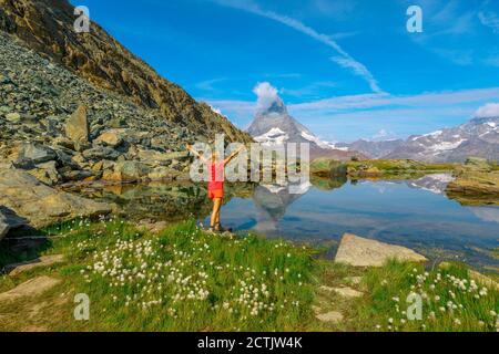 Les prairies alpines autour de Matterhorn se reflètent sur le lac Riffelsee. Femme touristique appréciant pendant le sentier de Riffelseeweg sur le chemin de fer à crémaillère de Gornergrat Bahn. Tourisme Banque D'Images