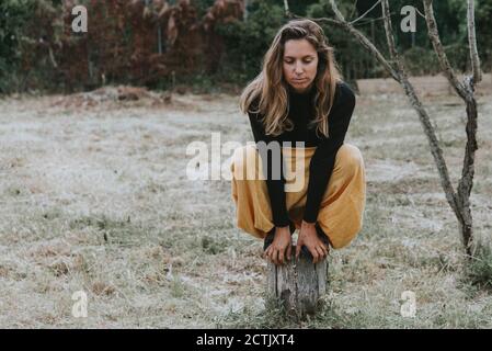 Femme attentionnés qui se balance sur une souche d'arbre dans le parc Banque D'Images