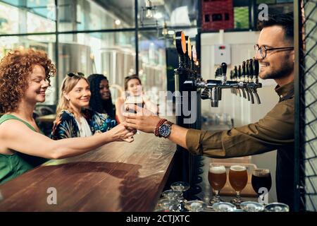 Barkeeper donnant un verre de bière à la femme dans un pub Banque D'Images