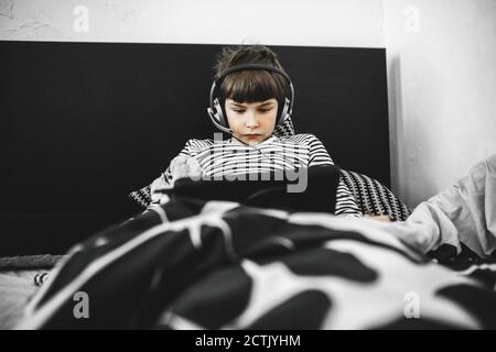 Bboy faisant le travail à la maison sur une tablette couché dans le lit Banque D'Images