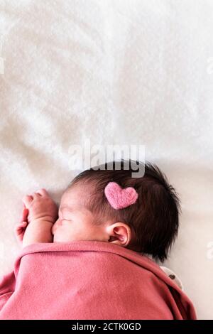 Nouveau-né bébé fille avec la forme de coeur sur la tête dormir lit à l'hôpital Banque D'Images