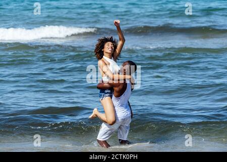 Romantique jeune homme transportant une petite amie en se tenant debout en mer Banque D'Images