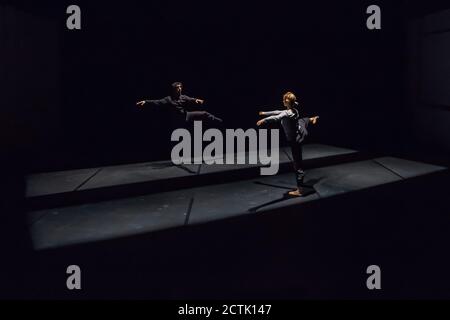 Danseuse masculine et féminine effectuant un ballet provisoire sur scène noire Banque D'Images