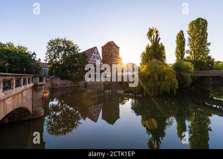 Allemagne, Bavière, Nuremberg, Weinstadel et Wasserturm se reflétant dans la rivière Pegnitz au coucher du soleil Banque D'Images