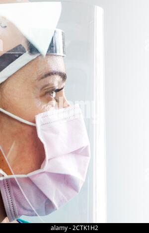 Gros plan du visage du médecin portant un masque et un visage de protection bouclier à la clinique Banque D'Images