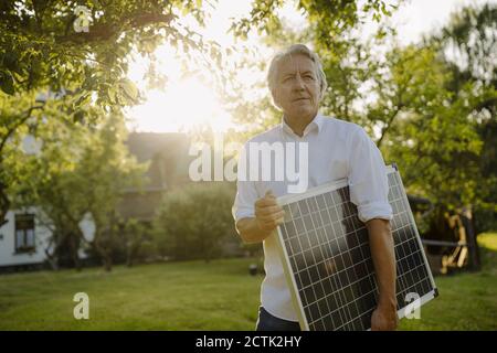 Homme froissé tenant un panneau solaire dans l'arrière-cour Banque D'Images