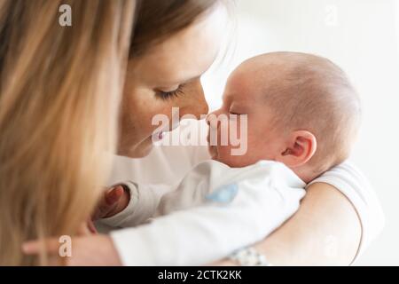 Gros plan de la mère embrassant bébé garçon endormi dans les bras à accueil Banque D'Images