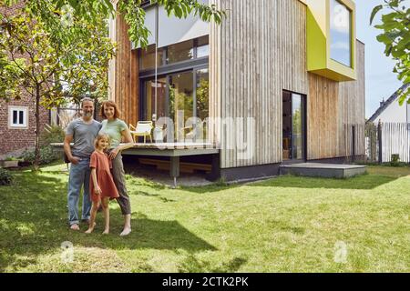 Famille debout à l'extérieur de la petite maison dans la cour Banque D'Images