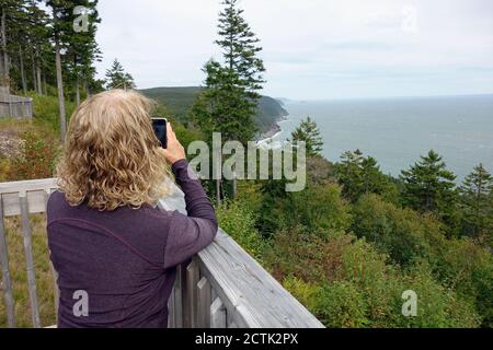 Femme prenant des photos le long de la côte au sentier de randonnée automatique de Fundy Trail Parkway, Nouveau-Brunswick, Canada Banque D'Images